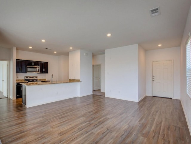 unfurnished living room with a sink, visible vents, wood finished floors, and recessed lighting