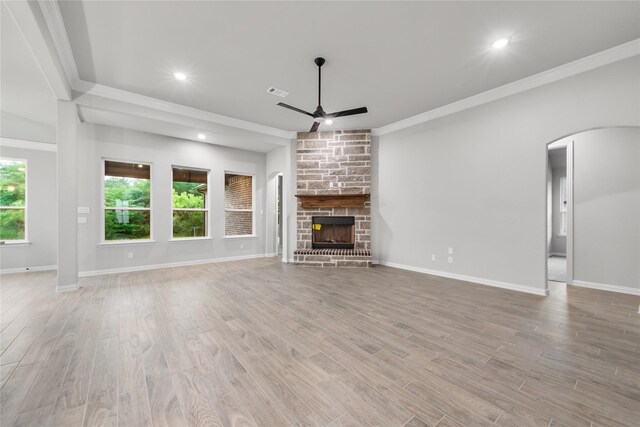 3915 Southern Oaks Dr, Royse City, TX 75189 - unfurnished living room featuring a ceiling fan, arched walkways, crown molding, wood finished floors, and a stone fireplace
