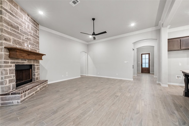 3915 Southern Oaks Dr, Royse City, TX 75189 - unfurnished living room with arched walkways, a ceiling fan, a large fireplace, light wood-style flooring, and ornamental molding