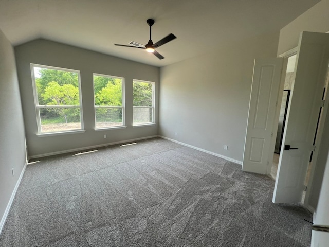 carpeted empty room with lofted ceiling, a ceiling fan, baseboards, and visible vents