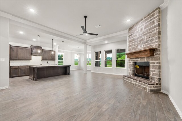 3915 Southern Oaks Dr, Royse City, TX 75189 - unfurnished living room with a ceiling fan, light wood finished floors, healthy amount of natural light, ornamental molding, and a fireplace