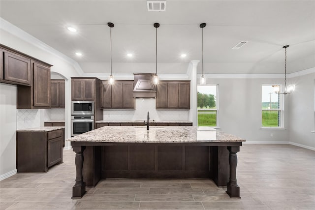 3915 Southern Oaks Dr, Royse City, TX 75189 - kitchen featuring stainless steel appliances, custom exhaust hood, dark brown cabinetry, backsplash, and a kitchen island with sink