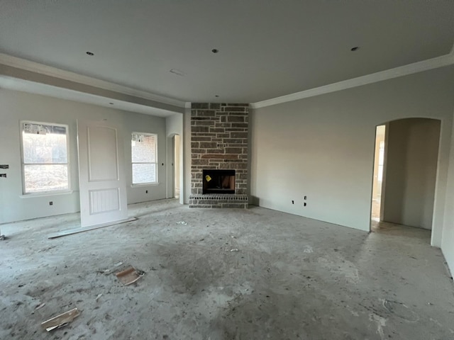 unfurnished living room featuring arched walkways, a stone fireplace, and crown molding