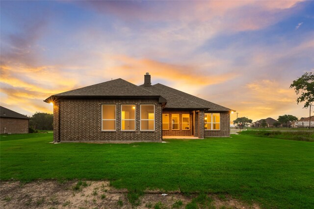 3915 Southern Oaks Dr, Royse City, TX 75189 - back of property at dusk featuring a chimney, a lawn, and brick siding