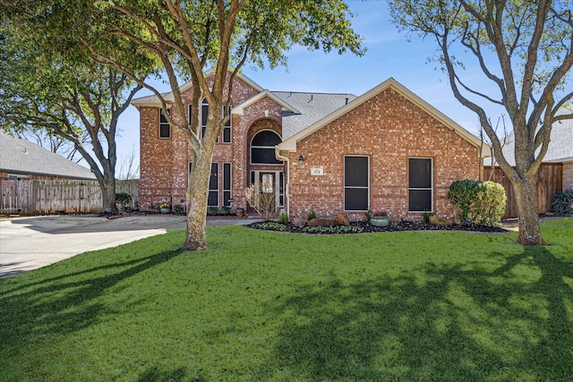 traditional home featuring brick siding, a front yard, and fence