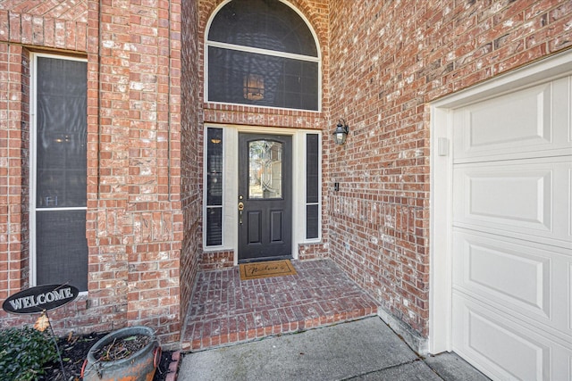 property entrance with brick siding and an attached garage