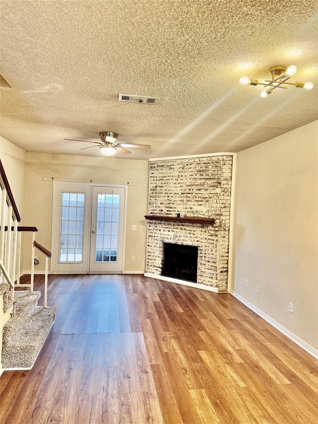 unfurnished living room with hardwood / wood-style flooring, a tiled fireplace, a textured ceiling, and ceiling fan