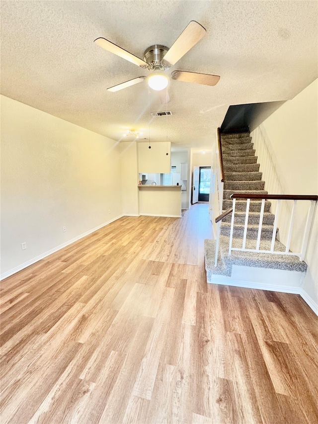 unfurnished living room featuring ceiling fan, a textured ceiling, and light wood-type flooring