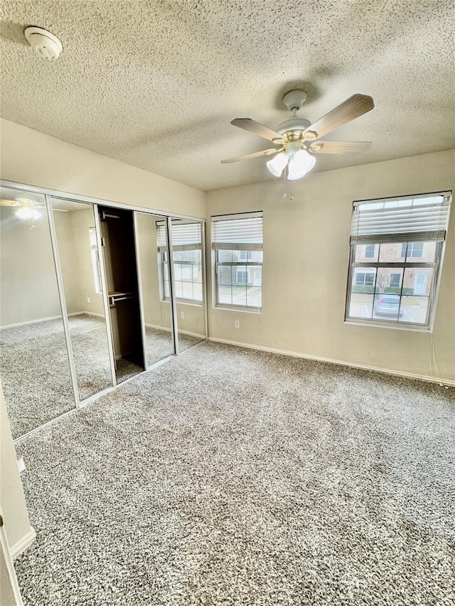 unfurnished bedroom with ceiling fan, carpet floors, a textured ceiling, and a closet