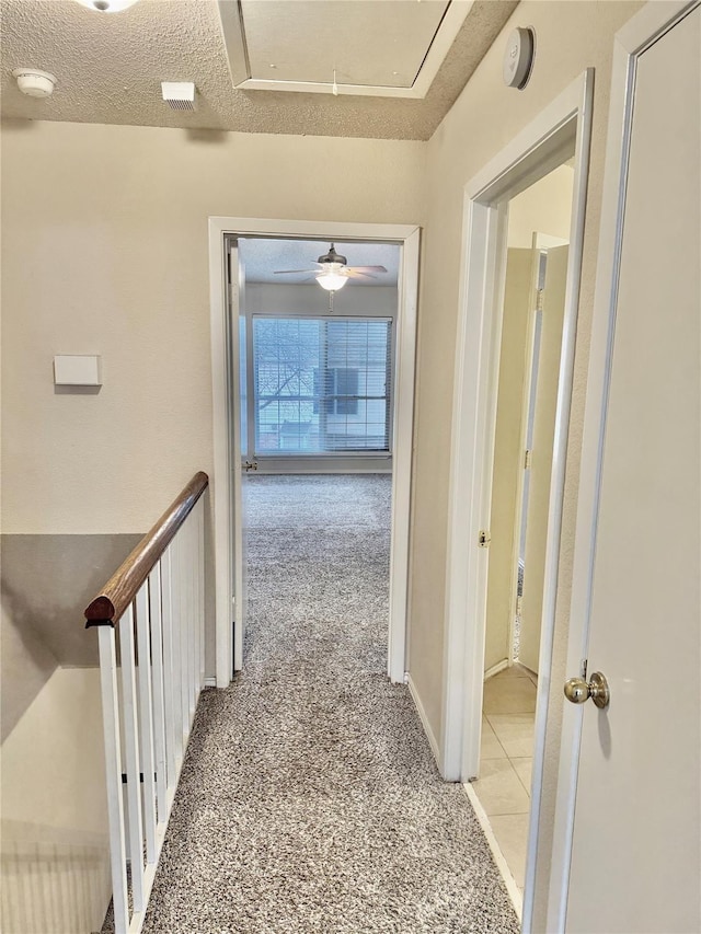 corridor with carpet and a textured ceiling