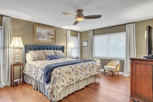 bedroom with ceiling fan, wood-type flooring, and multiple windows