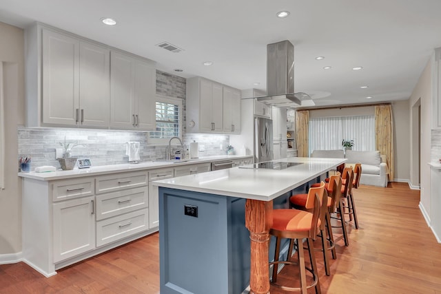 kitchen with sink, a center island, island range hood, and white cabinets