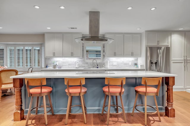 kitchen featuring a breakfast bar, island range hood, and a spacious island