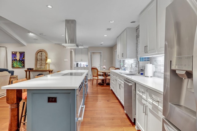 kitchen with island exhaust hood, a center island, white cabinets, and appliances with stainless steel finishes