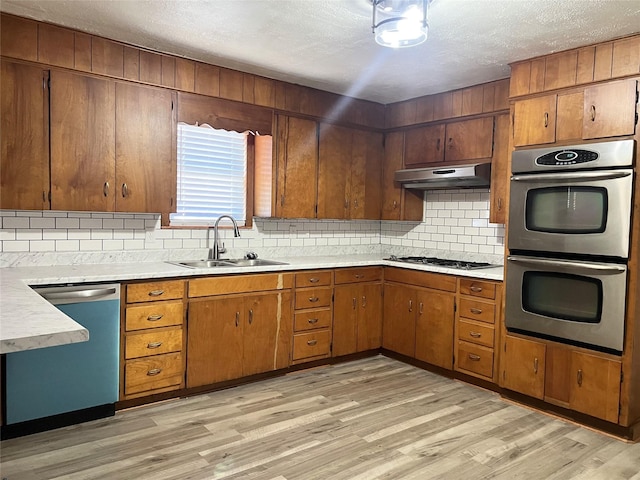 kitchen featuring tasteful backsplash, sink, light hardwood / wood-style floors, stainless steel appliances, and a textured ceiling