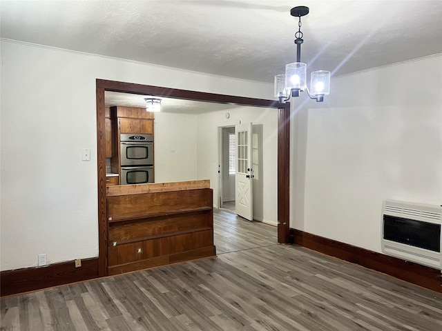 interior space featuring dark wood-type flooring, a chandelier, heating unit, and a textured ceiling