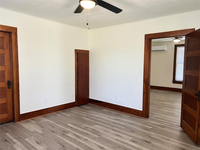 empty room with ornamental molding, a wall mounted AC, ceiling fan, and light hardwood / wood-style floors