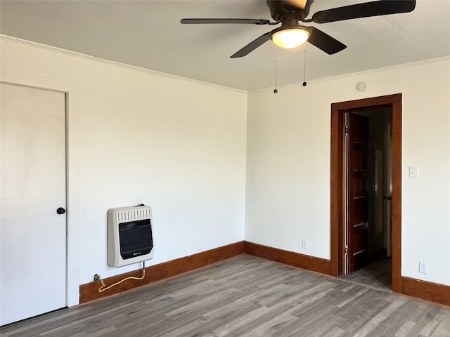 unfurnished room featuring hardwood / wood-style flooring, ceiling fan, crown molding, and heating unit