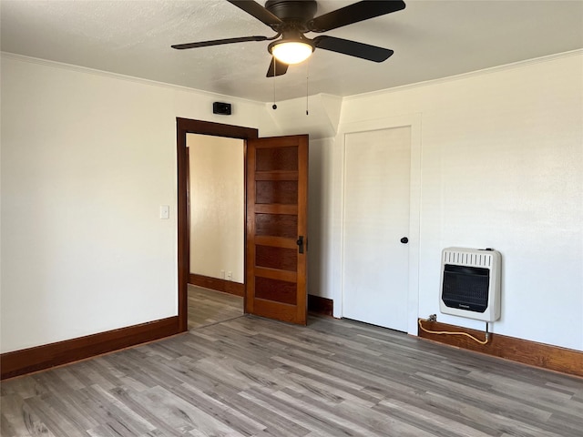 spare room with heating unit, hardwood / wood-style flooring, ornamental molding, and ceiling fan