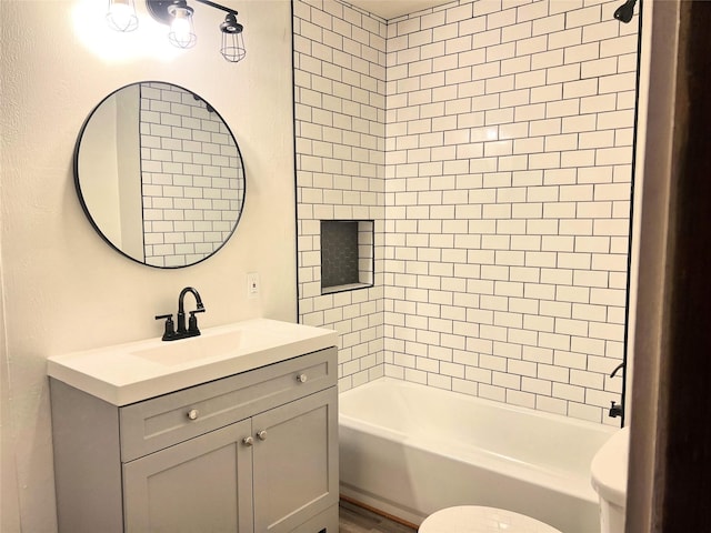 full bathroom featuring tiled shower / bath, vanity, and toilet