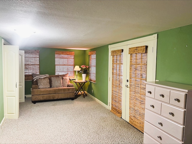 living area with french doors, a textured ceiling, and carpet