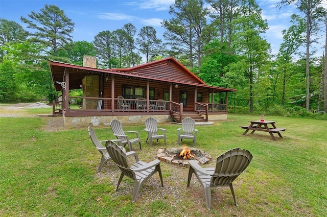 rear view of house featuring a porch, a fire pit, and a lawn