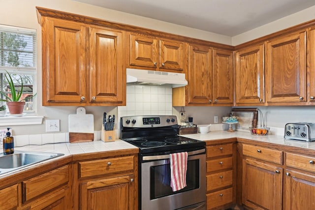 kitchen featuring tile countertops, stainless steel electric range oven, tasteful backsplash, and a wealth of natural light