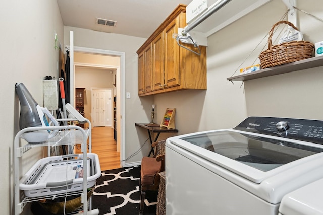 clothes washing area with cabinets, wood-type flooring, and separate washer and dryer