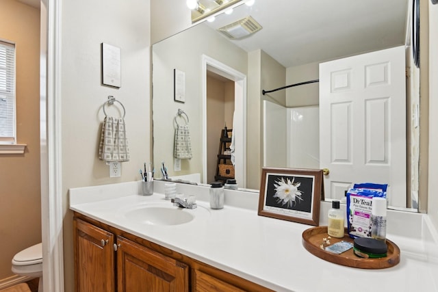 bathroom with vanity, a shower, and toilet