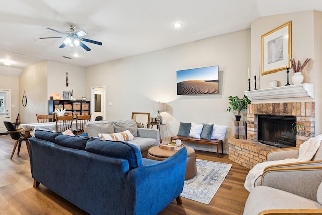 living room featuring hardwood / wood-style flooring, a brick fireplace, and ceiling fan