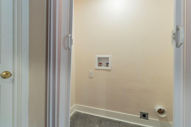 laundry room with electric dryer hookup, washer hookup, dark tile patterned floors, baseboards, and laundry area