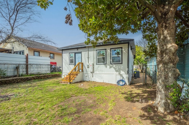 back of property featuring a lawn, central AC unit, and fence