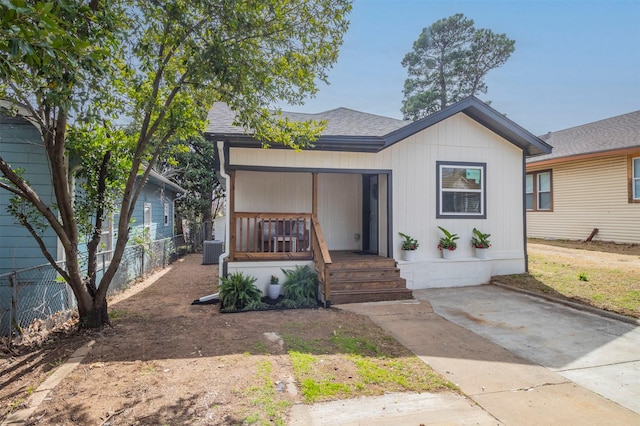 view of front of house featuring central AC unit, covered porch, a shingled roof, and fence