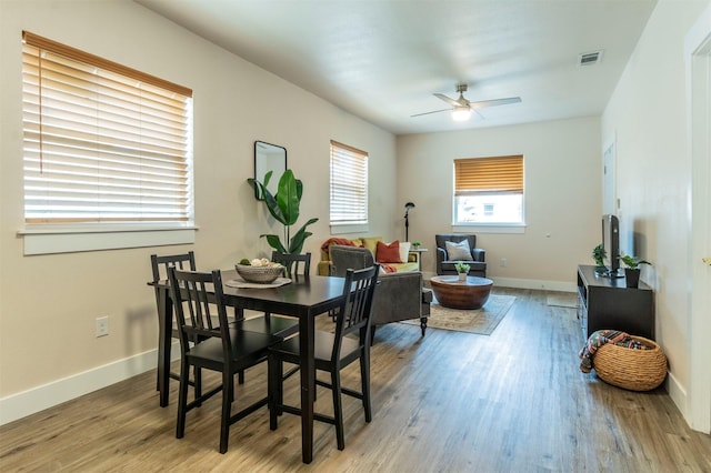 dining space featuring ceiling fan, visible vents, baseboards, and wood finished floors