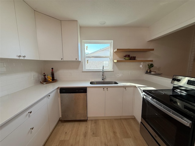 kitchen featuring white cabinetry, sink, light hardwood / wood-style floors, and appliances with stainless steel finishes