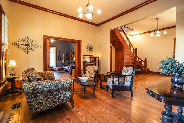 living room with wood-type flooring, crown molding, and an inviting chandelier