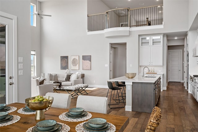 dining area featuring baseboards, a high ceiling, dark wood-style floors, and a ceiling fan