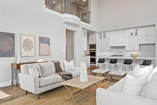 living area featuring a high ceiling, light wood-type flooring, and baseboards