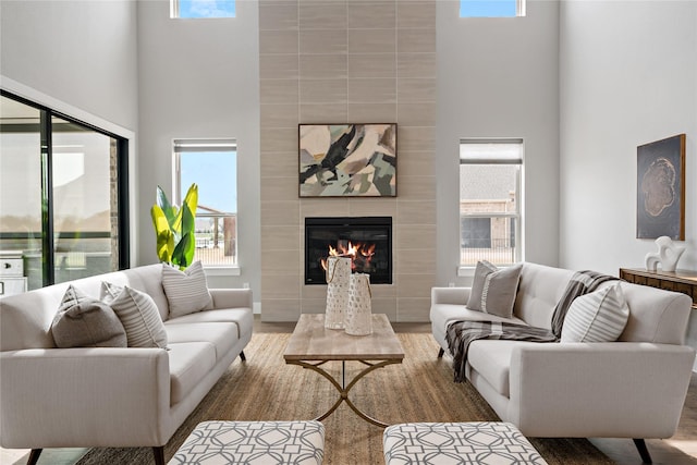 living room featuring a tiled fireplace, plenty of natural light, and wood finished floors