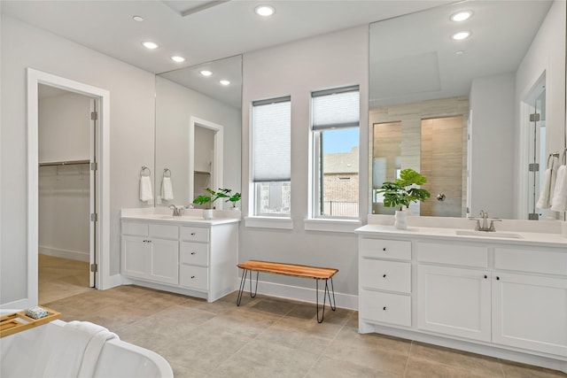 full bathroom with a tile shower, recessed lighting, and a sink