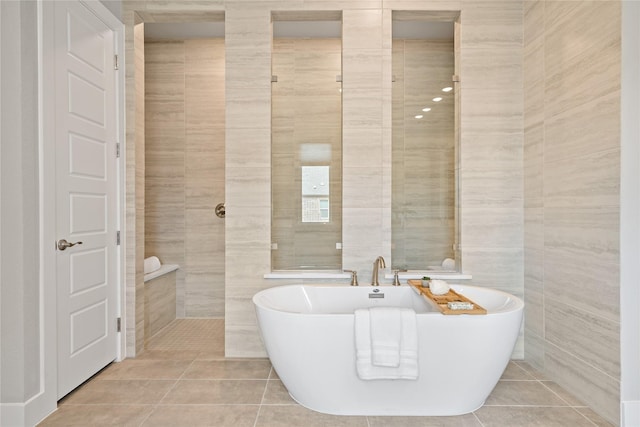 full bathroom with tile patterned floors, a freestanding tub, and tile walls