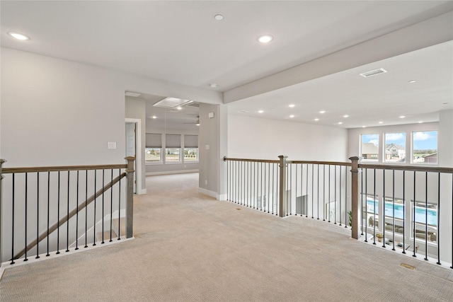 hall with attic access, recessed lighting, light colored carpet, and visible vents