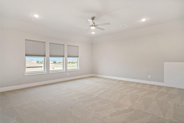 spare room featuring light colored carpet, baseboards, and ceiling fan