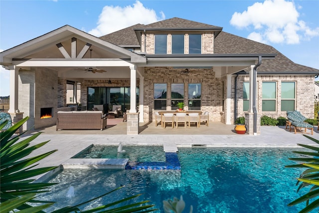 back of house with a ceiling fan, an outdoor living space with a fireplace, brick siding, and a patio area