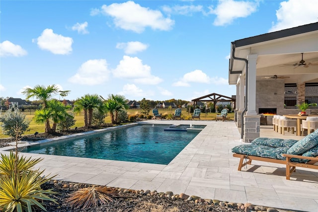 outdoor pool featuring a patio area, a gazebo, a large fireplace, and a ceiling fan