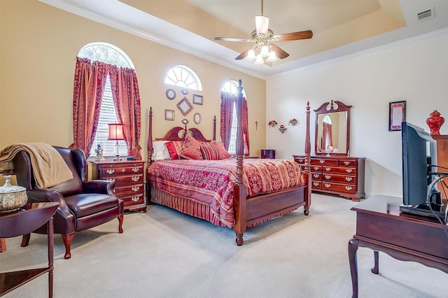 carpeted bedroom with a raised ceiling, ornamental molding, and ceiling fan