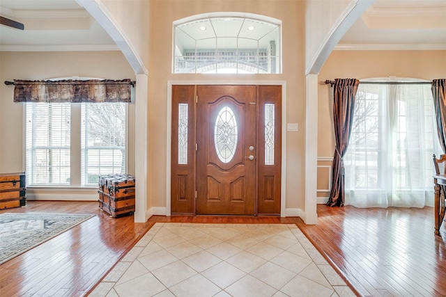 entryway with a raised ceiling, ornamental molding, and light hardwood / wood-style flooring