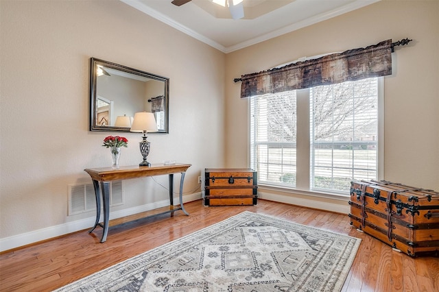 living area featuring hardwood / wood-style flooring, crown molding, and ceiling fan