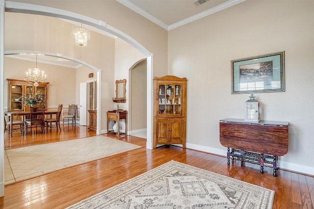 entryway featuring hardwood / wood-style floors, ornamental molding, and a chandelier