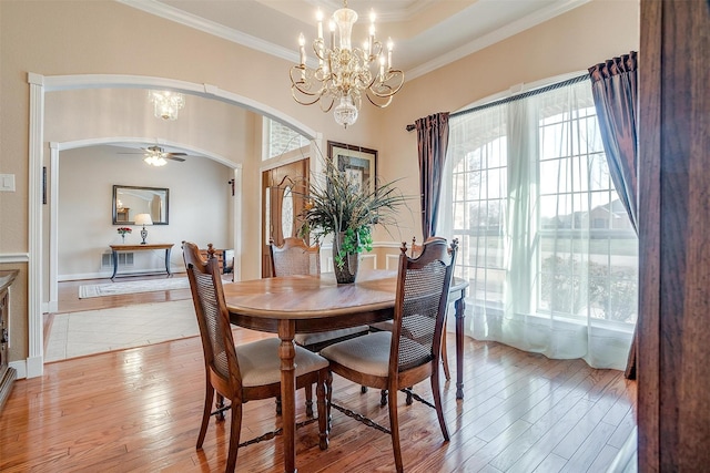 dining area with crown molding, a tray ceiling, light hardwood / wood-style floors, and a wealth of natural light